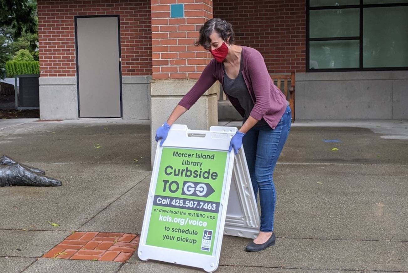A library staffer setting up a “Curbside to Go” sign. Photo courtesy KCLS