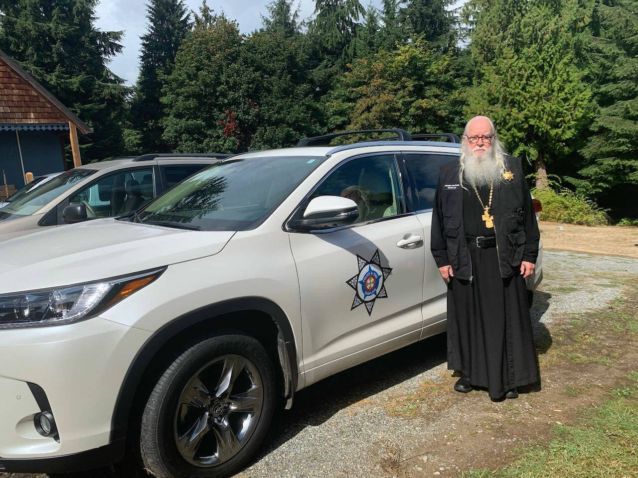 Courtesy Photo
Abbot Tryphon, of Vashon’s All-Merciful Savior Monastery, has long served as an unpaid fire and police chaplain on the island. In this photo, he is shown on the monastery’s grounds, standing by the vehicle he now uses to respond to calls.