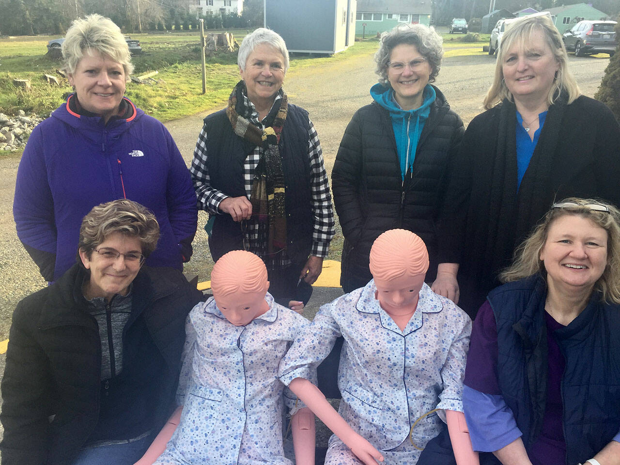 (Courtesy Photo) At a celebration last week, four HCA scholarship recipients, two of their trainers, and their training mannequins smiled for the camera. Top row left to right: Monica Dally, Sissel Johannessen (trainer), Stacey Wolczko, Chris Jovanovich (trainer). Bottom row left to right: Aimee Aiken, mannequins Thelma and Louise, and Holly Allingham. Two other students were not available as they were with clients.