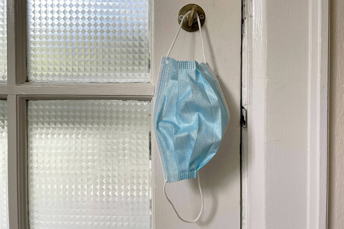 A protective mask hanging on a front door. (Sound Publishing file photo)