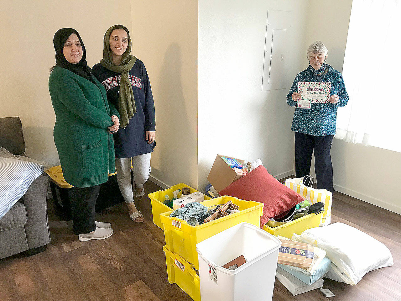 (Courtesy Photo) Earlier this year, VART delivered a household kit to the family of Nafisa Barez Saad. (Left to right) Nafisa, her teen daughter, and VART member Marian Brischle, with a welcome sign.
