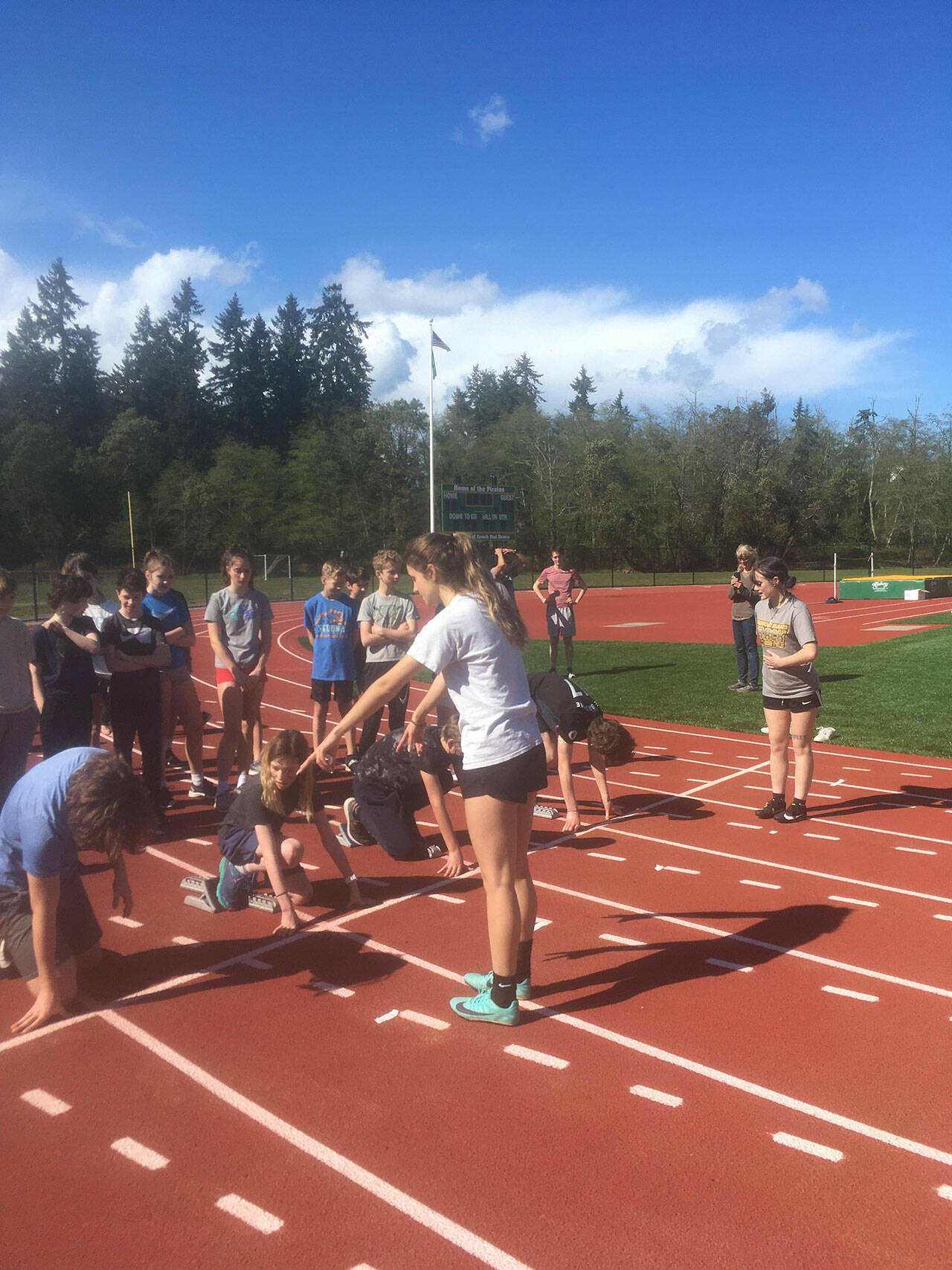 (Courtesy Photo) Senior team captains, Nicki Becker (left) and Phoebe Wilke (right) are mentoring the McMurray Mustang track team and instructing them on how to use starting blocks.