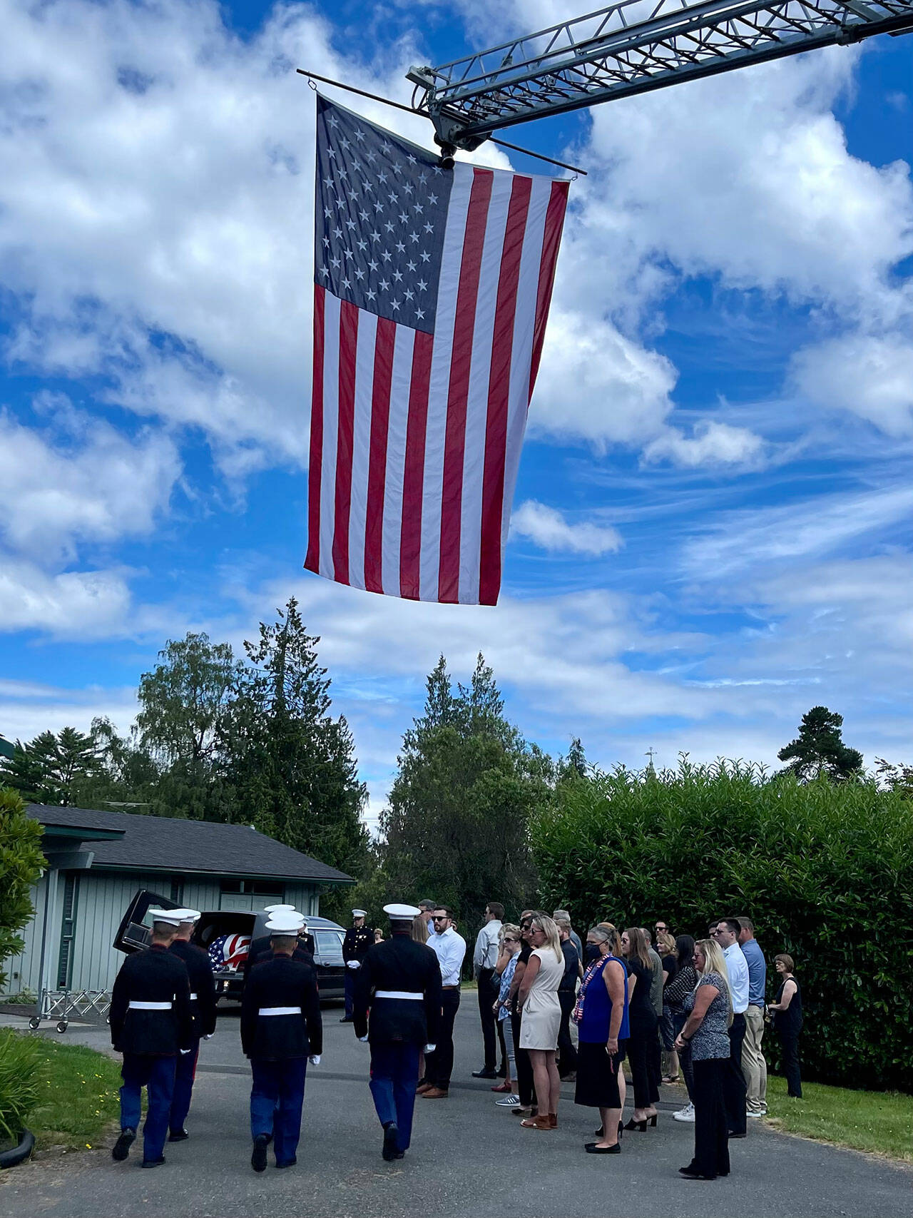 (Jim Whitney Photo) A solemn procession for islander Sam Yates concluded at Island Funeral Service, where an American flag was unfurled on Vashon Island Fire & Rescue’s ladder truck.