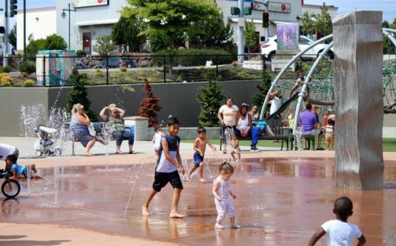Families splash and play in the water at at Federal Way’s Town Square Park to cool off from a previous heatwave in the region. (Sound Publishing file photo)