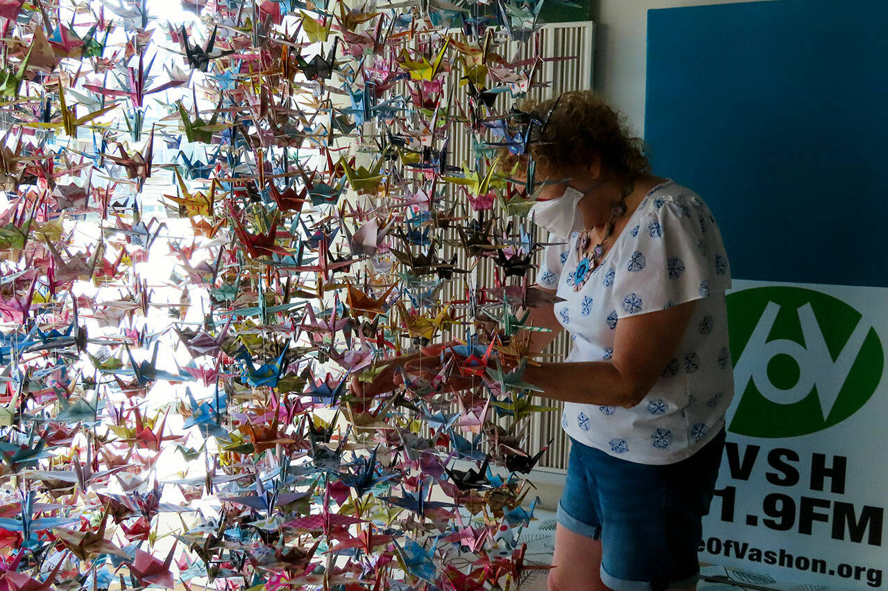 Alice Larson straightened the origami cranes on her artwork after moving it to Voice of Vashon. (Peter Ray Photo)