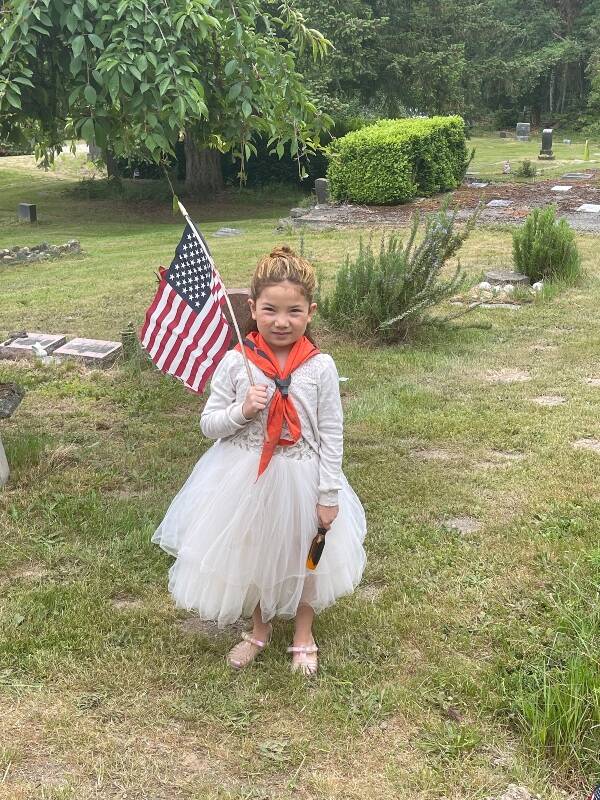 Hazel Ecevedo, 7, from Cub Scout Pack 275, helped place American flags on the graves of veterans in Vashon Cemetery on Saturday, prior to Memorial Day (Lisa Devereau Photo).