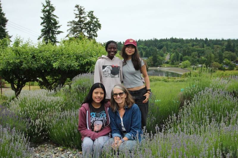 Cathy MacNeal, lower right, poses for a photo among the lavender with the 2023 summertime interns (clockwise from lower left) Jeyli Castañon, Victoire Soumano and Ava Lee on June 13 (Olivia Sullivan Photo).