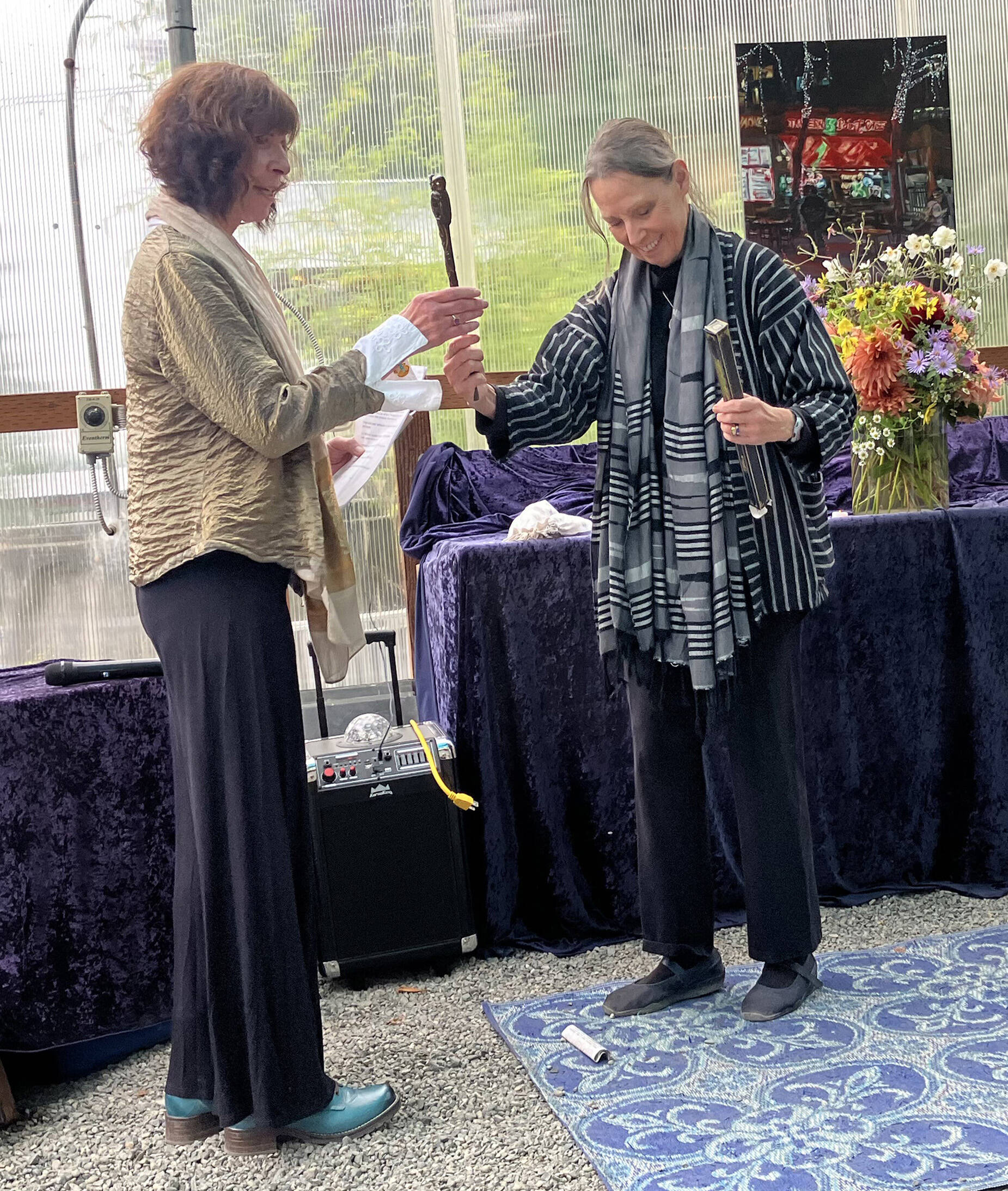 Sandra Noel passes the Vashon Poet Laureate wand to Margaret Roncone (Elizabeth Shepherd Photo).