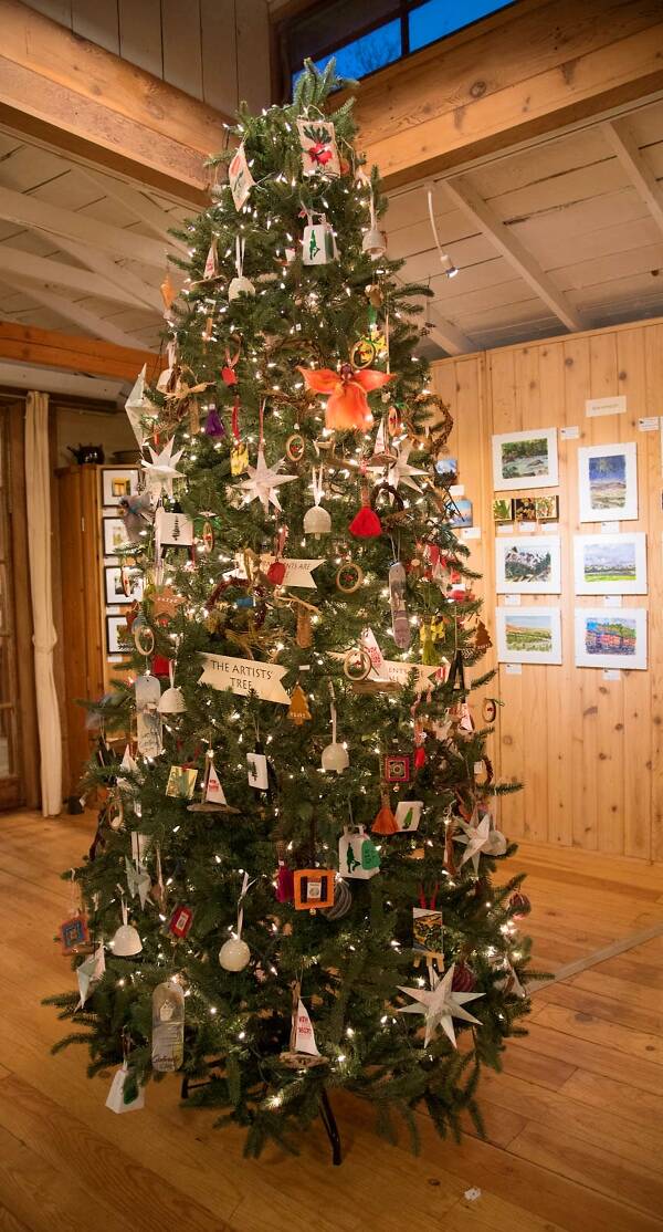 An “artist’s tree” stands just inside the studio’s door — a dazzling evergreen festooned with lights and small, inexpensive artworks by each member of the Waterworks collective (Courtesy Photo).