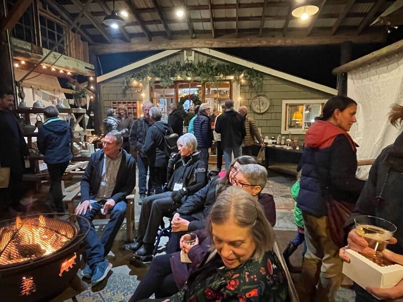 Longtime local artists Brian Fisher and Christine Beck (seated, center of photo) held court around a fire pit at Waterworks Studio during a preview party for the Vashon Island Studio Art Tour (Adrienne Edmonson Photo).