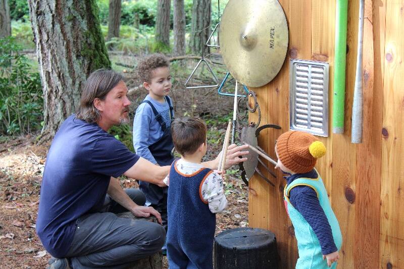 TJ Moore instructs kids at Island Outdoor School to play at the music wall without hitting the instruments too hard. “One of the themes of outdoor schools is, instead of just having toys around it, you create stations for them to go and play with,” Moore said. “You can add to , you can change” (Alex Bruell photo).