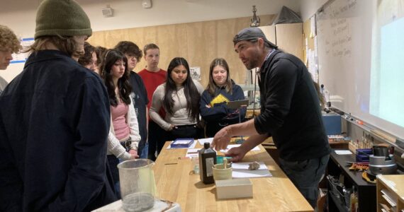 Vashon High School jewelry and chemistry students gather around Dr. Joshua Marceau as he discusses metallurgy. (Courtesy Photo)