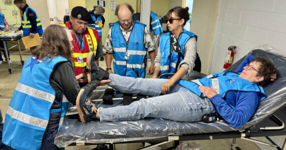 Clayton Olney Photo
Volunteers practice stabilizing a patient at the Medical Reserve Corp’s field treatment site at Sunrise Ridge. Left fo right: Paul McGowan (in background), Chris McGrath, Will Dacus, Sarah Day (in background), Jim Hunziker, Megan Yeager, and Lisa Crosby on the gurney.