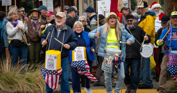 Islanders drum and wave signs along Vashon Highway during Saturday’s “No Kings Day” protest. (Kent Phelan Photo)