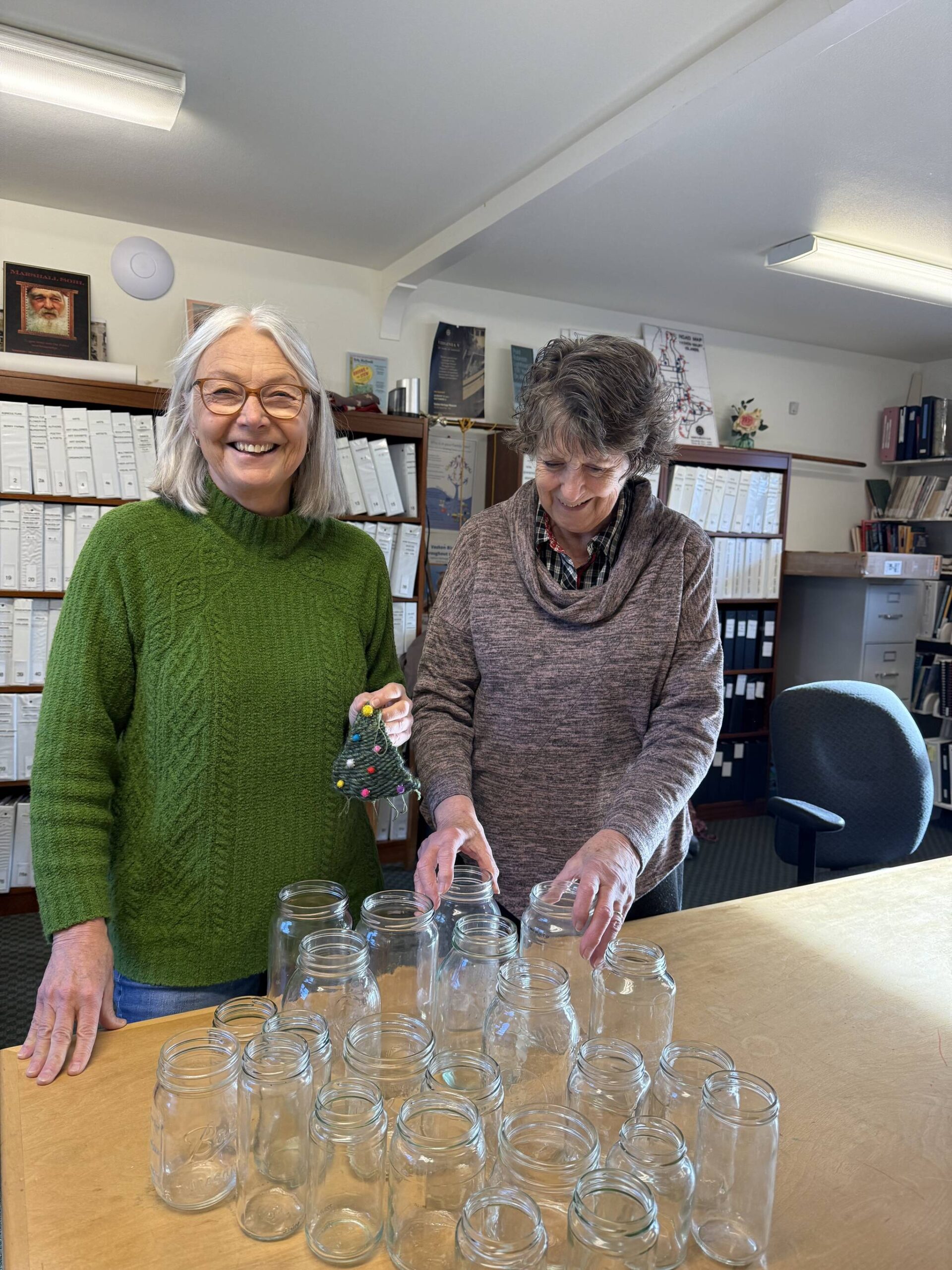 Vashon Heritage Museum volunteers, Susan Martin and Jenny Lewis, with supplies for the the museums Family Day on Dec. 20. Children will have the opportunity to decorate a glass jar with tissue paper for a colorful lantern. Susan is holding a woven ornament, another craft opportunity for families. (Courtesy Photo)