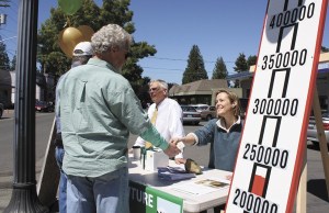 School board member Kathy Jones accepts money from Islander Tag Gornall while school Superintendent Michael Soltman talks about the district’s financial crisis with another Islander.
