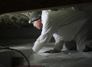 Carlos Romero from Aqueous Basement Solutions puts down a new vapor barrier in a crawlspace at Eernisse.