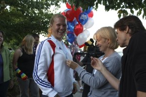 Islanders Lisa Huggenvik (center) and Kim Goforth take a close look at Mia Croonquist's gold medal at a surprise celebration for the rowing champion Monday night.