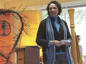 Rev. Carmen McDowell at a Sunday worship. Behind her is harpist Leslie McMichael.