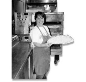 Natalie Harkins pauses with a pizza before sliding it in to bake.