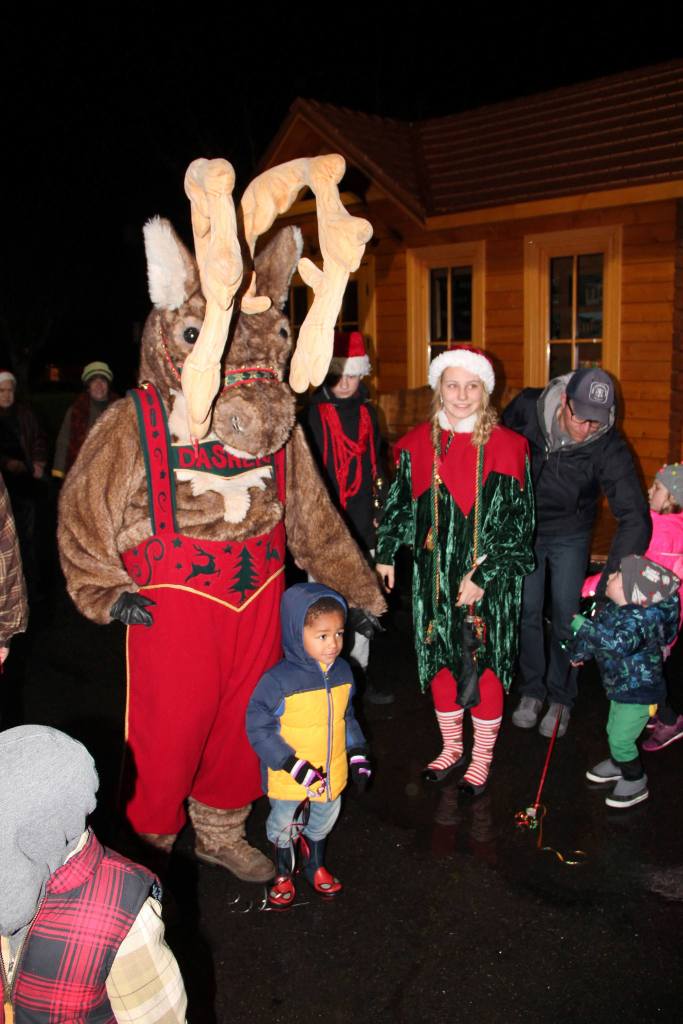 A child takes a photo with Dasher the Reindeer Saturday night. (Susan Riemer/Staff Photo)