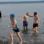 Decked out in bathing caps and swimsuits, participants make their way to the fires on shore. (Anneli Fogt/Staff Photo)