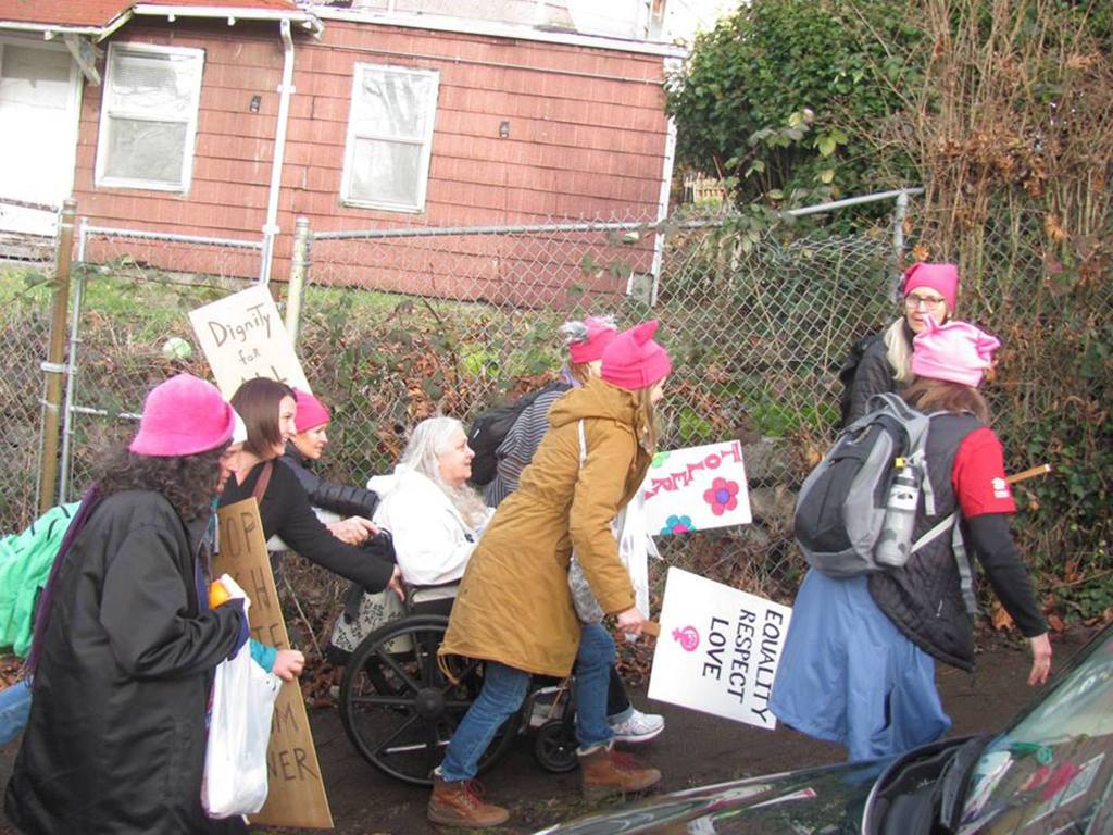Islanders are among those who help a woman in a wheelchair get up a steep hill to Judkins Park before the start of the Seattle march (Bob Jonas Photo)