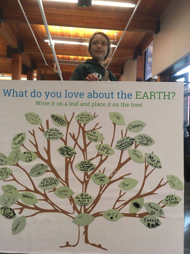 An island student holds a sign which asks attendees to write down what the love about our planet. Answers include oxygen, trees, colors, people and biodiversity. (Judy Twedt Photo)