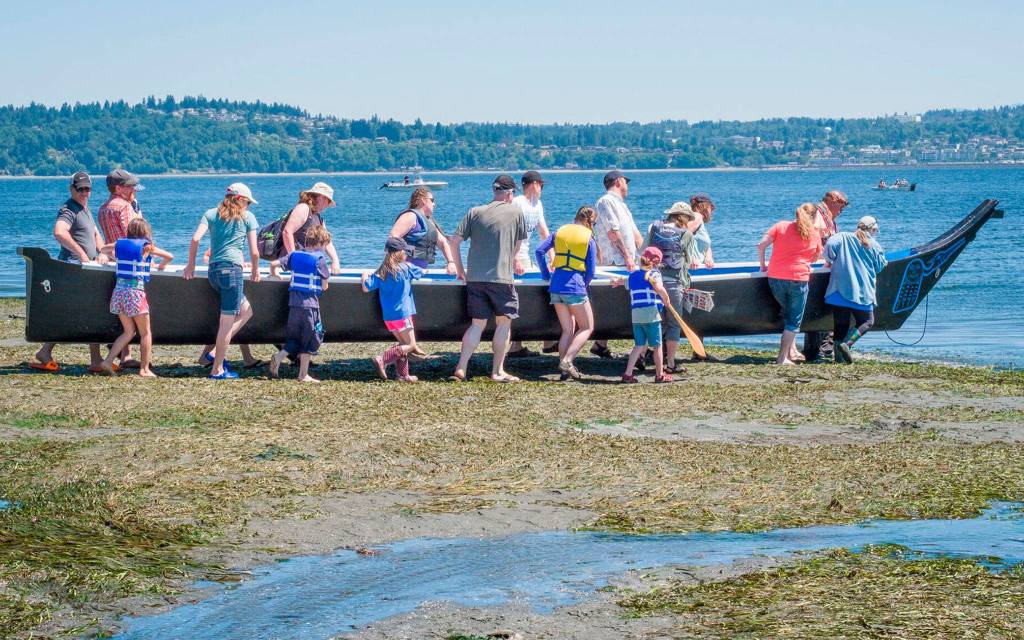 A group of people carry the Snohomish Tribe&rsquo;s Blue Heron Canoe into the sound. (Kent Phelan Photo)