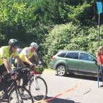 Islanders and friends Bob Horsley (left) and Bruce Morser (right) ride through a ribbon set up by friends at Jensen Point last Saturday, marking the end of their 4,300-mile bicycle journey across the country. (Juli Goetz Morser Photo)