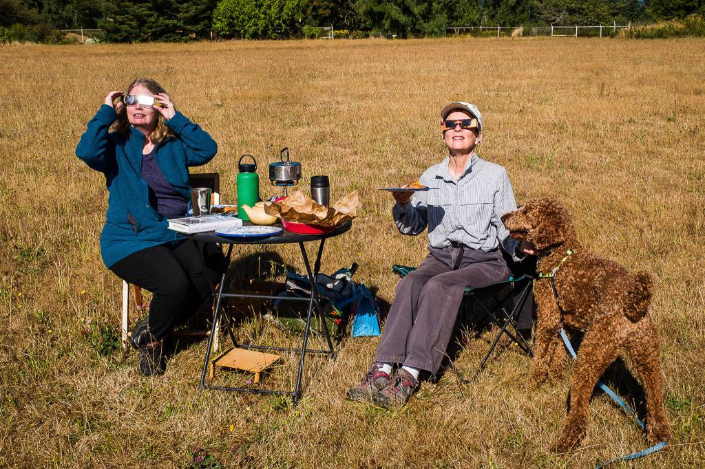 Two women enjoy a picnic with their dog at Vashon&rsquo;s Sunrise Ridge during Monday&rsquo;s solar eclipse. (Kent Phelan Photo)