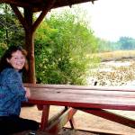 Laurie Bevin Stewart, author of On Fisher Pond: Memories of Bill Fisher and His Gift to Vashon Island,&rdquo; sits at the pond in the center of Vashon. (Juli Goetz Morser/Staff Photo)