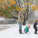 Flanked by a tree still displaying autumn color, children play in the snow in front of the Vashon Library Sunday afternoon. (Anneli Fogt/Staff Photo)