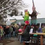 Wearing wings and waving the U.S. flag, Unofficial Mayor Tink, Colleen Carette, leads Saturdays crowd in song following the march from Center to the Village Green. Joining her in leading the music were Leila Khatapoush, in the green jacket, and Linda Thorson in the pink hat. (Susan Riemer/Staff Photo)