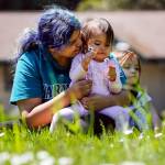 Lavennah Shongutsie hugs daughter Moniqueah Shongutsie-Wesley in the afternoon sun at Forest Park in Everett on Thursday. Temperatures are expected to reach 80 degrees this weekend. (Kevin Clark / The Herald)