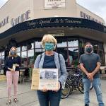 From left: Elsa Croonquist, Sue Hardy and Brian Brenno stand in front of the historic building now housing The Hardware Store Restaurant  a stop on the Main Street Vashon: A Walk through History, a new, self-guided walking tour presented by the Vashon Heritage Museum (Tom Hughes Photo).