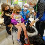 (Rick Wallace Photo) It seemed like Chia the dog and her handler, Molly Purrington (right), knew what Pippa Stendahl (left) needed  a little eye contact as she sat on her moms (Sophia Stendahl) lap. Pippa and Chia locked gazes, and from there, it was a smooth operation as Medical Reserve Corps volunteer nurse Lorraine Chambers (center) sensed the relaxed moment and completed the injection.