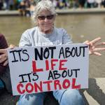 A woman sits with a sign at the reproductive rights protest on May 14, 2022, at Cal Anderson Park. Hannah Saunders/Sound Publishing