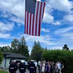 (Jim Whitney Photo) A solemn procession for islander Sam Yates concluded at Island Funeral Service, where an American flag was unfurled on Vashon Island Fire & Rescues ladder truck.