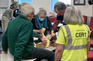 Courtesy photo
Preparing a disaster victim for transport: A class of 16 new Community Emergency Response Team (CERT) students finished up their nine-week basic training course recently. In this hands-on first aid exercise, the team practices applying a splint to "victim" Dick Danielson with a knee injury. From left to right: Marie Koltchak and Denis Snow do their work under the watchful eye of CERT veteran Sharon Danielson.