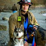 Photo by Milo Bailey
Vashon Island Fire and Rescue Lieutenant Ben Steele kneels next to Kirby, the dog that Steele and his VIFR crew rescued from a cliff at KVI beach last week.