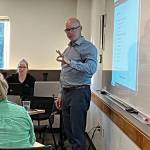 Superintendent Slade McSheehy asks a question of Amy Sassara, human relations director of Vashon Island School District (back to camera) at a school board meeting on April 18, while presenting a list of possible staff cuts in the district (Elizabeth Shepherd Photo).
