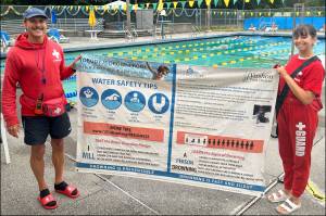 Megan Yeager (right), Vashon Park District lifeguard, swim instructor, and Vashon Seals Swim Team assistant coach, holds a banner of water safety tips with lifeguard colleague Michael Wish Wishkoski. At a bare minimum, every child should learn how to float, Yeager said. (Courtesy photo.)