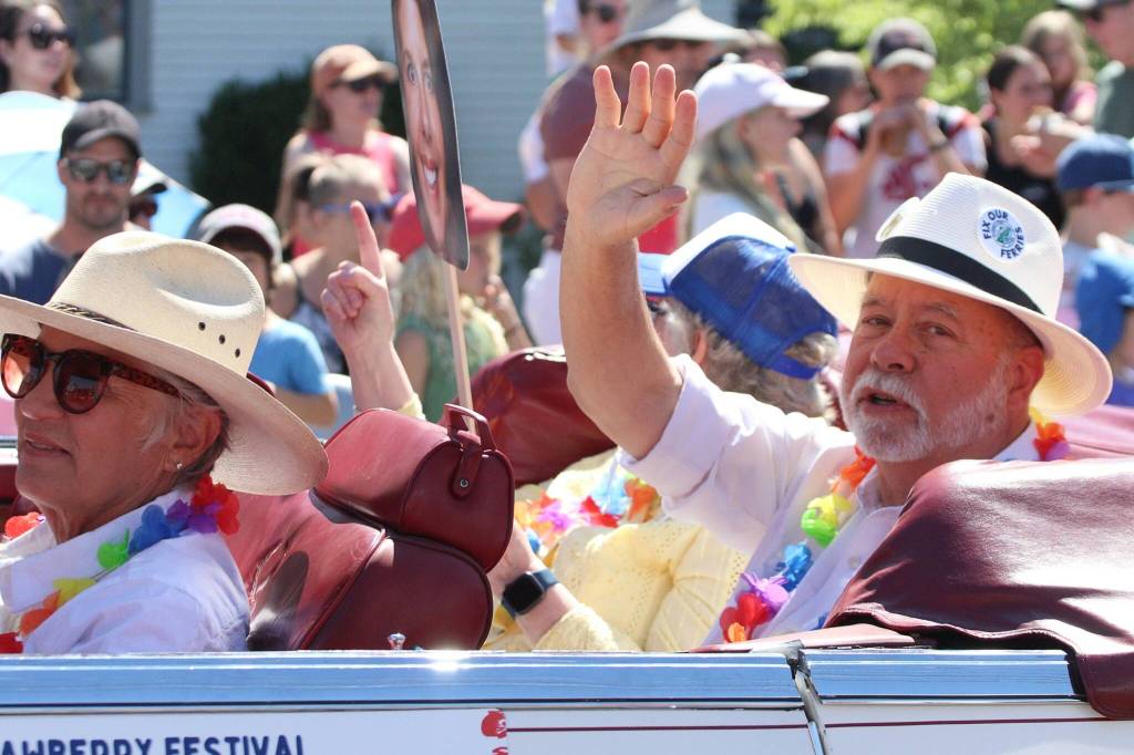 Islanders for Ferry Action volunteer steering committee members Wendy Aman, Beth Lindsay and Rick Wallace roll down Vashon Highway as the Grand Marshals of the 2024 Strawberry Festival parade. The trio are dedicated activists and islanders who have in the last year helped improve the islands troubled ferry service. (Alex Bruell photo)