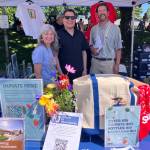 Andrew Guillen (Cahuilla/Luiseño), the chief public affairs officer of Seattle Indian Health Board (center) is flanked by islanders Yve Susskind (left) and Joseph Bogaard (right), representing Friends of Thunderbird, at the Health Boards Strawberry Festival booth. (Elizabeth Shepherd photo)