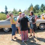 Pepa Brower (in striped pants, center) hobnobbed with friends in front of her husband Dre Neeleys prized vintage Cadillac. The couple owns Gravy, a noted restaurant on Vashon. (Tom Hughes photo)