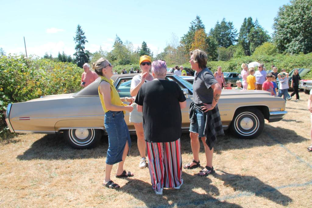 Pepa Brower (in striped pants, center) hobnobbed with friends in front of her husband Dre Neeleys prized vintage Cadillac. The couple owns Gravy, a noted restaurant on Vashon. (Tom Hughes photo)