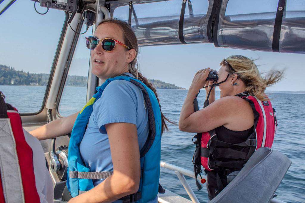 World Vets Field Responder EJ Verble prepares to make landfall while Vashon Nature Center Science Director Bianca Perla looks for the remains of the gray whale through her binoculars. (Alex Bruell photo)