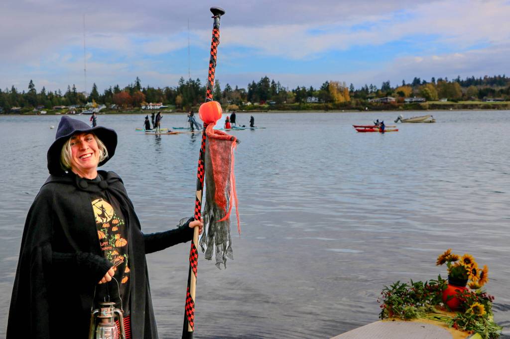 A witch pauses on shore, her paddle in hand and hat tilted just right, before joining the Halloween paddle on the waters. (Aspen Anderson photo)