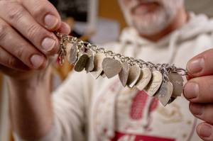 Grannys Attic Executive Director Brian Vescovi holds up a bracelet recently donated to the thrift store that carries names and dates of more than a dozen loved ones. (Alex Bruell photo)